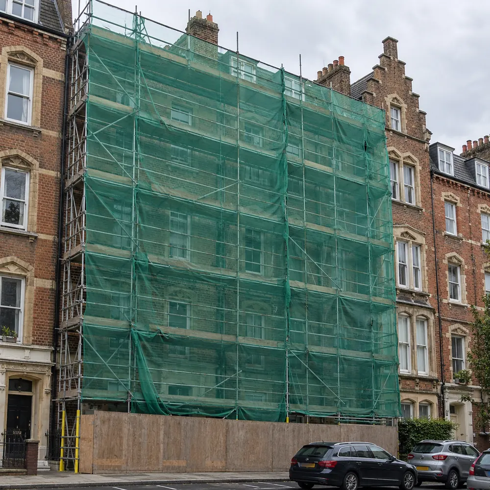 Scaffolding on a building facade covered with green debris netting